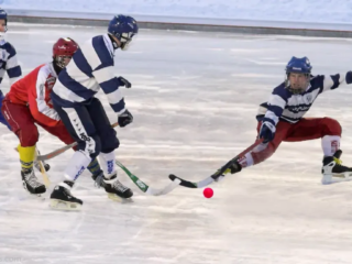 Игроки в хоккей с мячом соревнуются за мяч в высокоскоростной игре на льду, требующей частых рывков и быстрого ускорения в сочетании с элементами футбола и хоккея